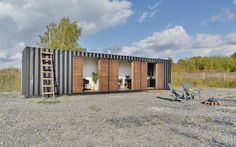 a house made out of shipping containers sitting on top of a gravel field