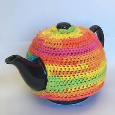 a crocheted tea pot cover with a black handle