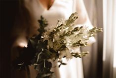 a woman holding a vase filled with white flowers