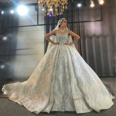 a woman in a wedding dress standing next to a chandelier