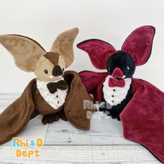 two stuffed animals dressed in costumes sitting next to each other on a white wooden floor