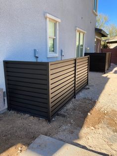 a house that has a black fence in front of it and some dirt on the ground