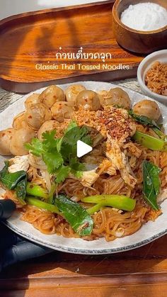 a white plate topped with noodles and veggies on top of a wooden table