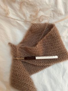 a hair brush laying on top of a bed next to a piece of cloth and thread