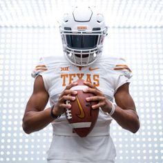 a man holding a football in his hands and wearing a uniform with the word texas on it