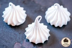 three small white seashells sitting on top of a black table next to each other