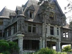 an old house with stone and wood trimmings on the front, surrounded by greenery