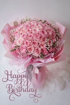 a bouquet of pink roses on top of a white surface with the words happy birthday written in cursive writing