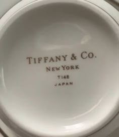 a white porcelain plate with the words tiffany & co in black lettering on it's side