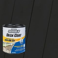 a can of deck coat sitting on top of a black wooden fence with the lid open