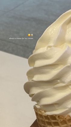 an ice cream cone with white frosting on it sitting on a table next to a sidewalk