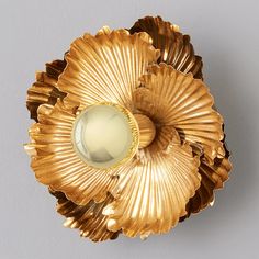 a gold flower shaped object with a glass centerpiece in the shape of a shell