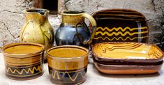 several vases and bowls sitting on a table next to each other with designs painted on them