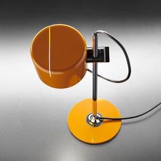 an orange table lamp with a black cord attached to the base and a white light on top