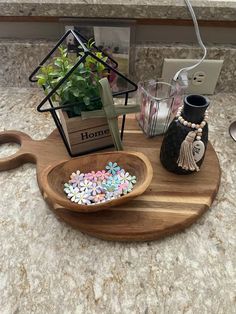 a wooden tray with flowers and beads in it sitting on a counter top next to a candle holder