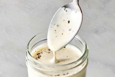 a spoon full of mayonnaise being drizzled over the top of a jar