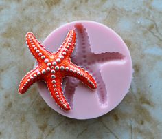 an orange and white starfish sitting on top of a pink plastic molding tray