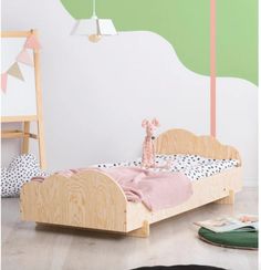 a small child's bed with pink and green decor on the wall behind it