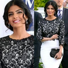 a woman in a black and white dress is smiling at the camera while standing next to a man wearing a suit