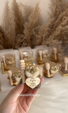 a hand holding a tiny bottle with flowers in it and some small bottles on the table