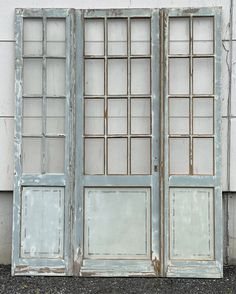 an old window with glass panes on the outside and inside, sitting in front of a white wall