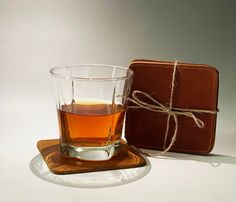 a glass of tea sitting next to a brown case on a white surface with a rope