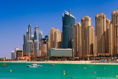 the city is surrounded by tall buildings and blue water, with boats in the foreground