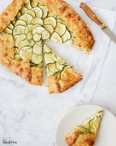 a pie with zucchini and cheese on it next to a slice cut out