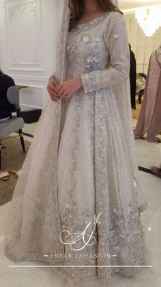 a woman in a white gown and veil standing on the floor with her hand on her hip