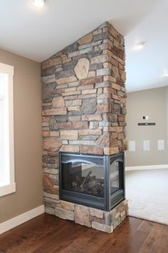 an empty living room with a stone fireplace