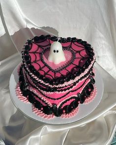 a heart shaped cake decorated with black and pink icing, topped with a spooky ghost