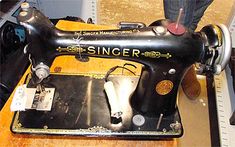 an old sewing machine sitting on top of a wooden table next to a person's feet