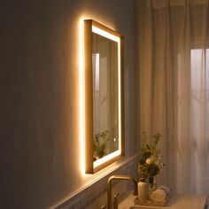 a bathroom sink under a lighted mirror next to a window