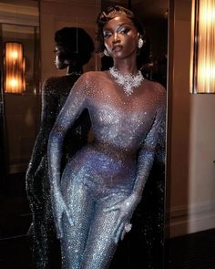 a mannequin dressed in blue and silver glitter is standing next to a mirror