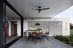 an outdoor dining area with table, chairs and ceiling fan on the side of the house