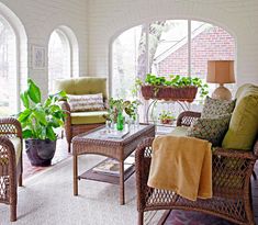 a living room with wicker furniture and potted plants on the table in it