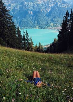 a person laying in the grass on top of a hill