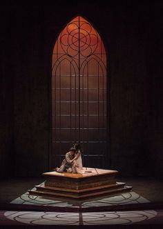 two people sitting on a platform in front of a stained glass window