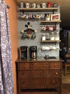 there is a coffee maker on top of the dresser in this room with shelves and mugs