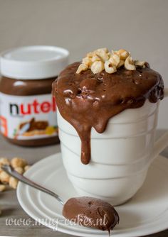 chocolate ice cream with nuts on top in a white cup and saucer next to it