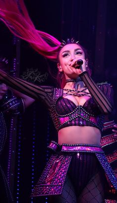 a woman with pink hair is performing on stage