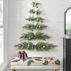 a small christmas tree is hanging on the wall next to a bench with presents under it