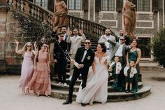 a group of people standing around each other in front of a staircase with confetti