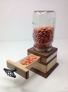 a glass jar filled with lots of red and white rocks sitting on top of a wooden stand