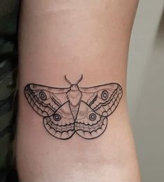 a small moth tattoo on the side of a woman's leg, with black ink