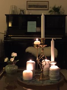 candles are lit on a table in front of a piano