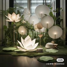 an assortment of white paper lamps on display in a room with green carpet and plants