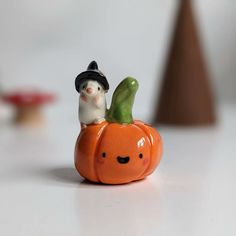 a small figurine is sitting on top of a pumpkin with a man in a hat