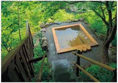 there is a small pond in the middle of the woods with trees around it and steps leading up to it