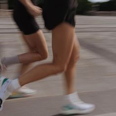 two people are running down the street in shorts and sneakers, one is wearing white socks